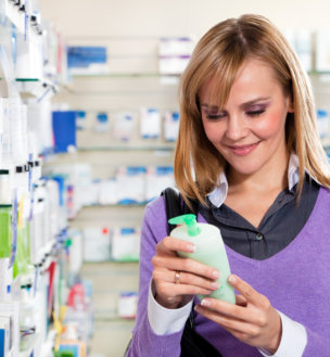 a woman in a pharmacy, carefully examining a bottle of soap
